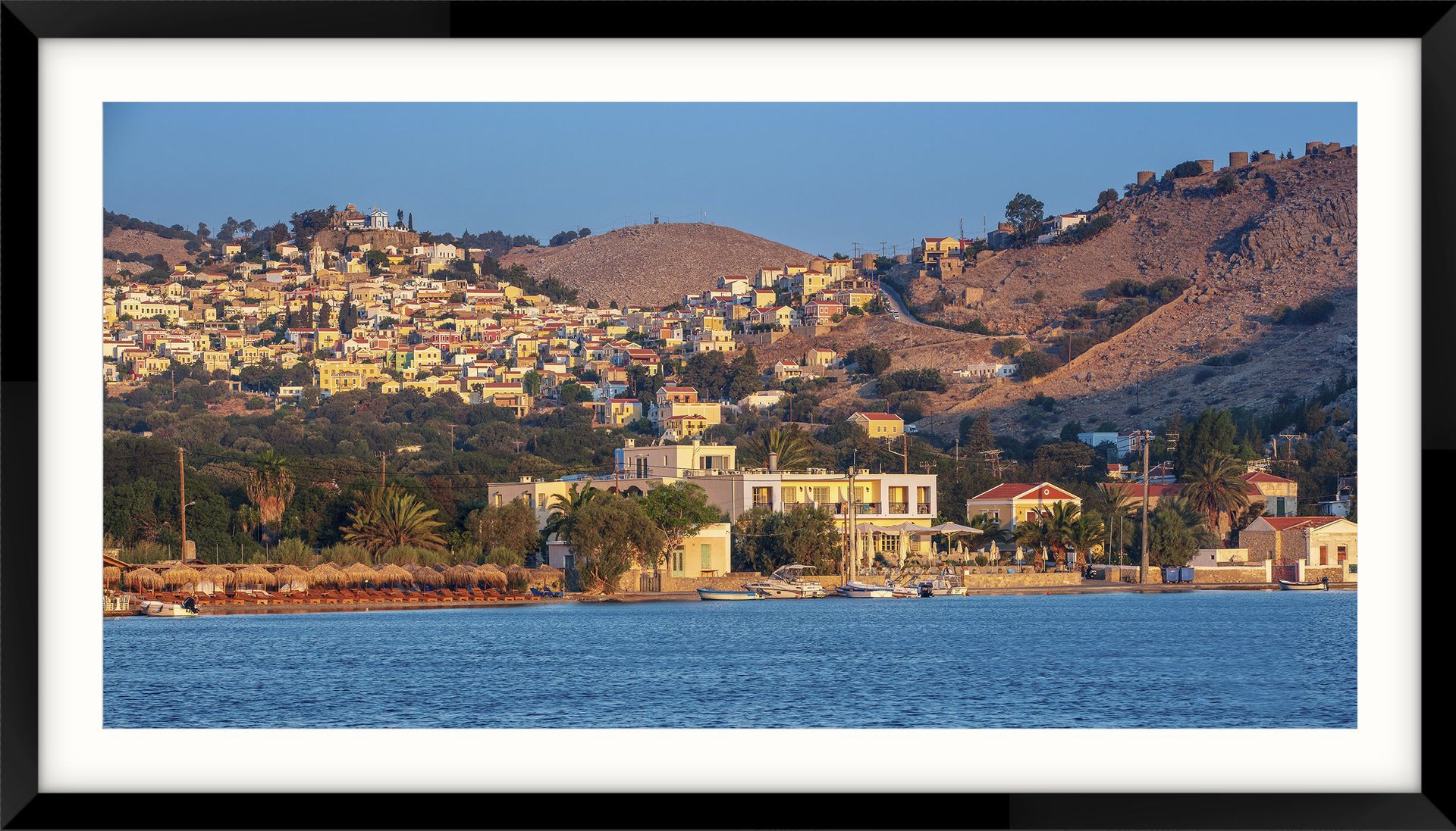 Symi Island Greece, a framed picture of a small town on a hill overlooking a body of water