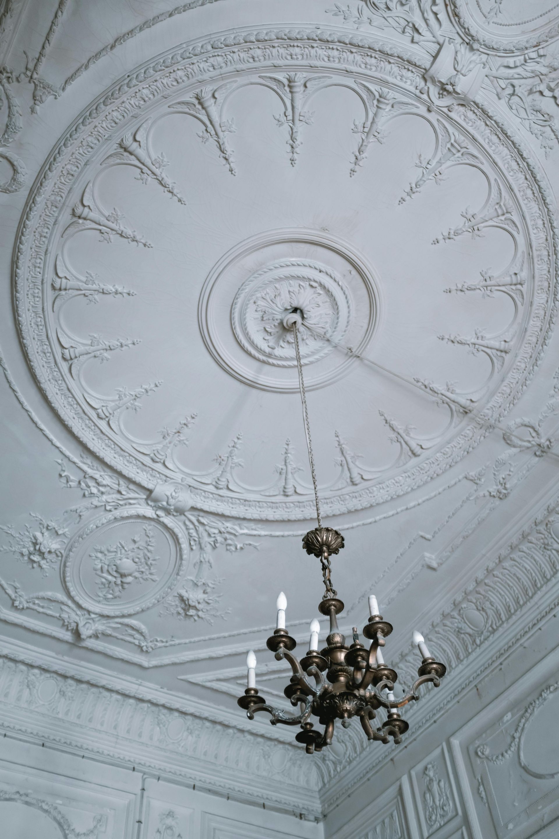 Ornate white ceiling with chandelier hanging from a circular design.