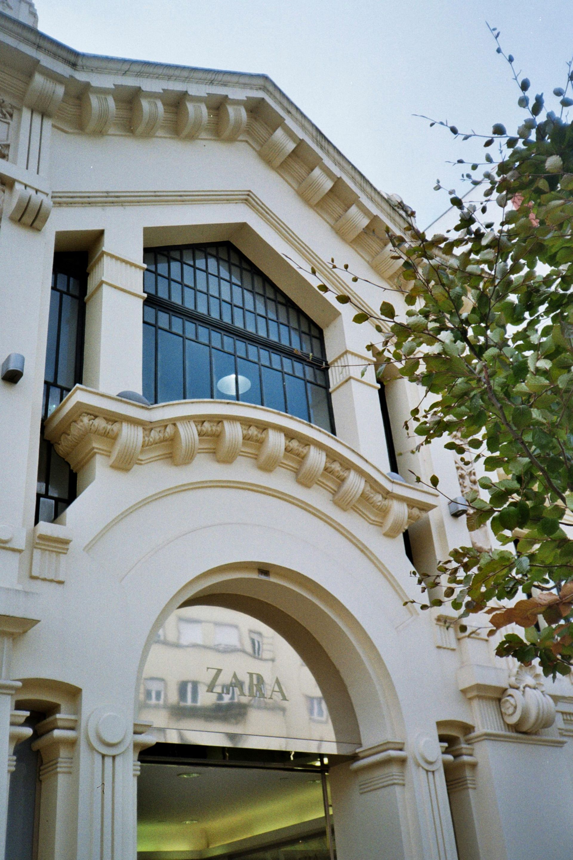 Ornate white building facade with arched entrance and large geometric window.