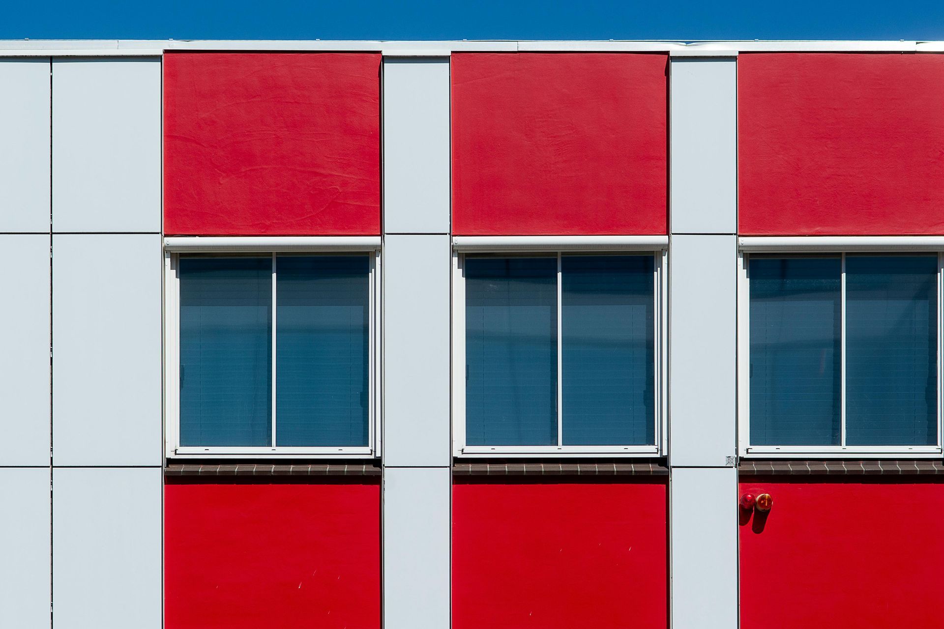 Three windows on red and white building facade.