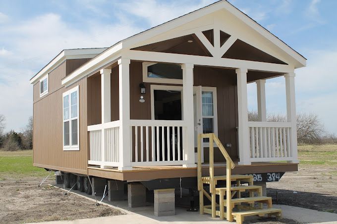 A small brown house with a white porch and stairs