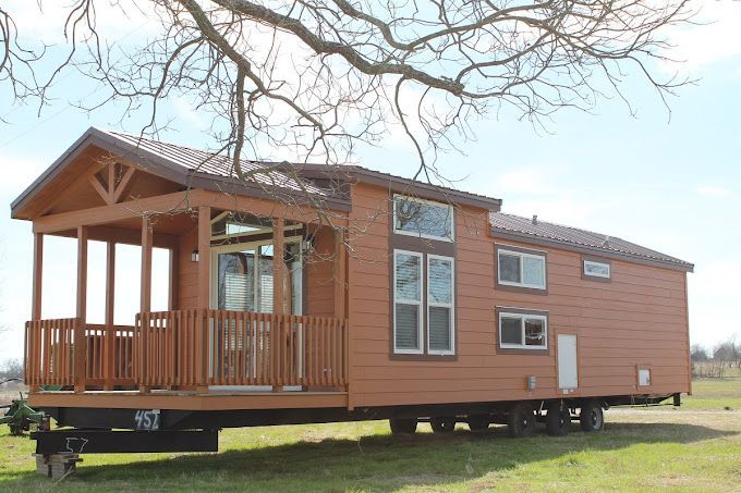 A tiny house on wheels is parked in a grassy field.