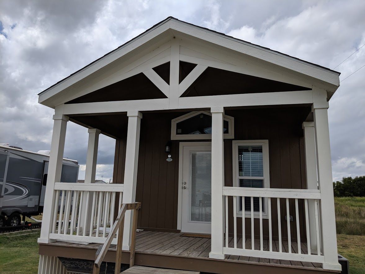 A small brown and white house with a porch and stairs.