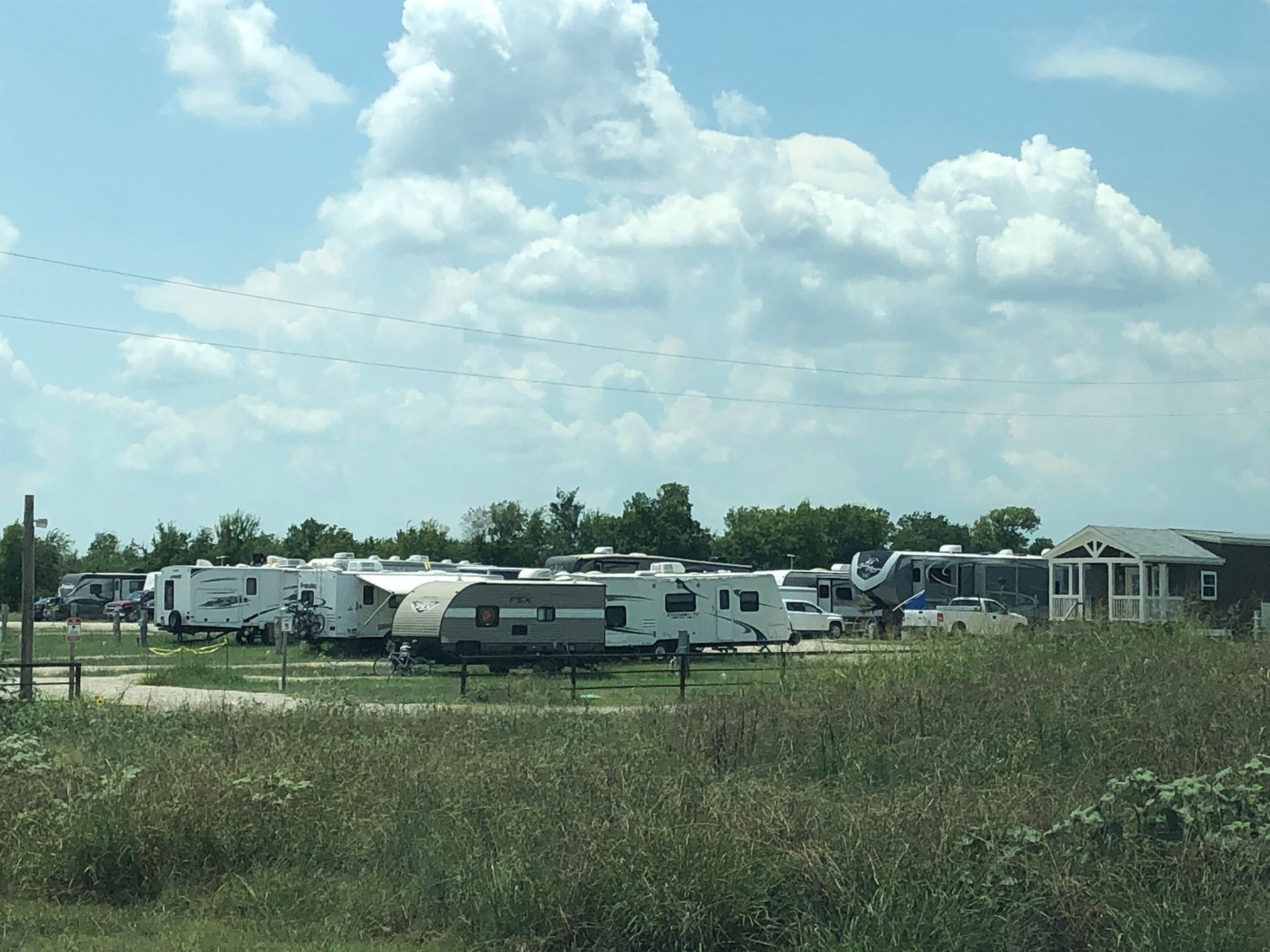 A row of rvs are parked in a field on a sunny day.