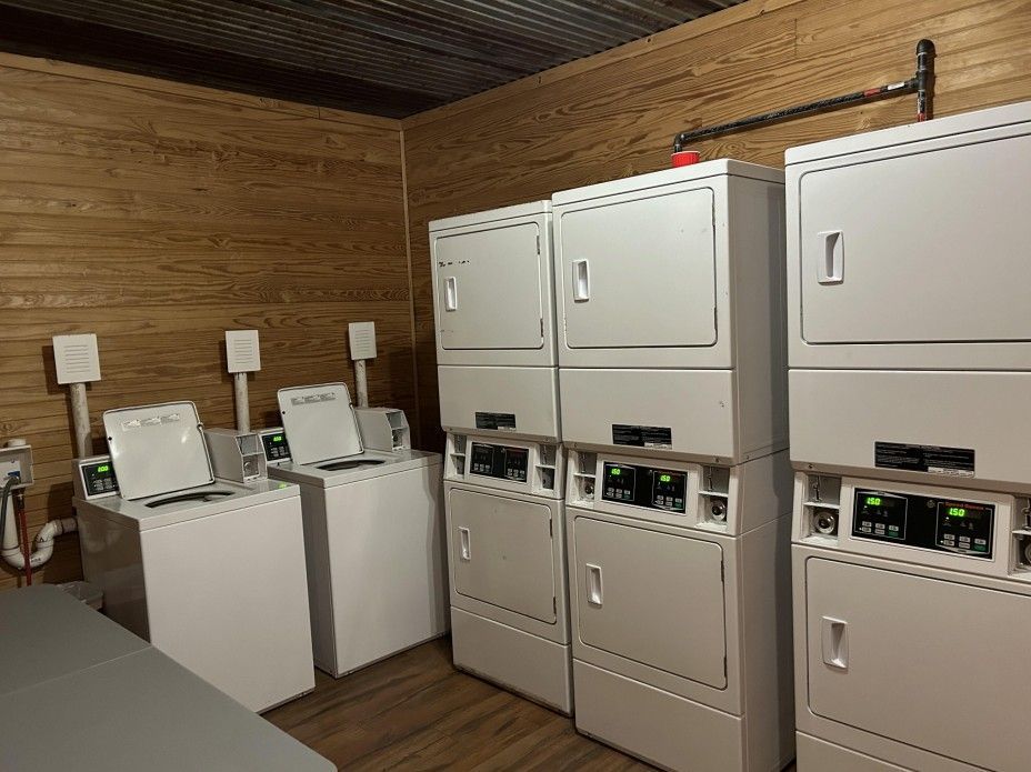 Laundry room with washers and dryers against a wood-paneled wall.