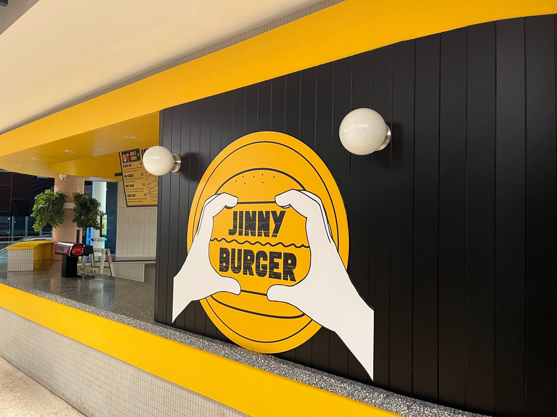 A restaurant counter with a yellow circular logo featuring two hands holding 
