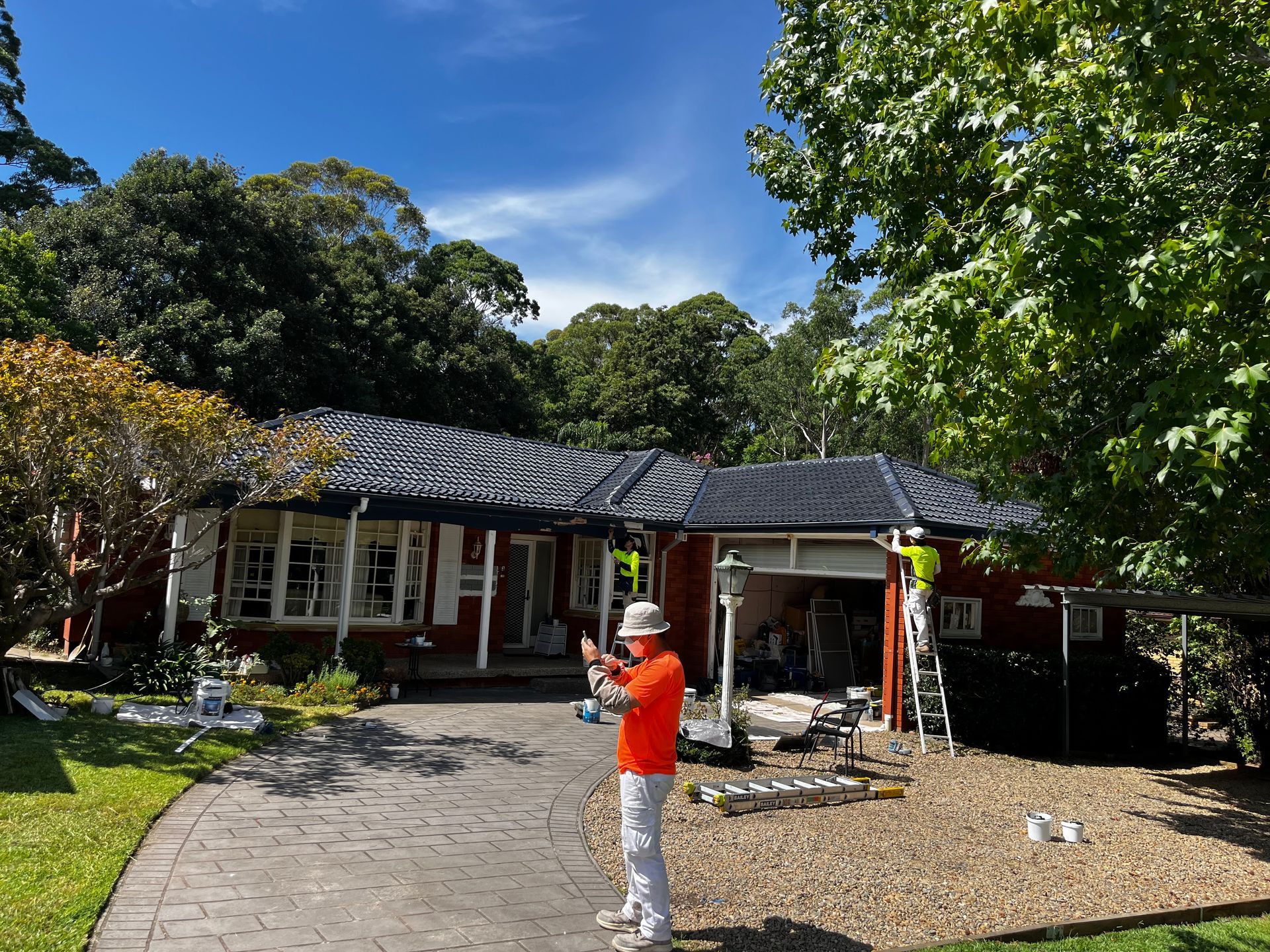 A power tool lies on a pitched, weathered concrete tile roof next to a ridgeline pointed with white mortar.