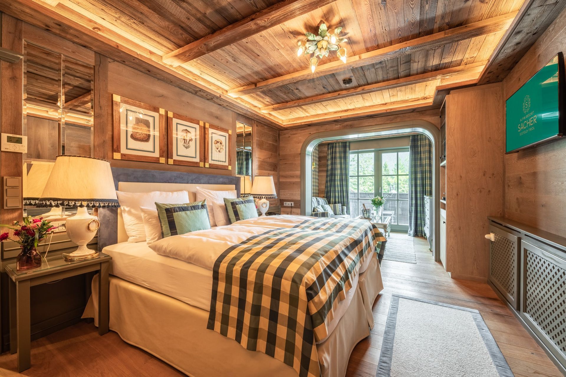 Cozy hotel bedroom with wooden walls and ceiling, a large bed with striped blanket, and balcony access.