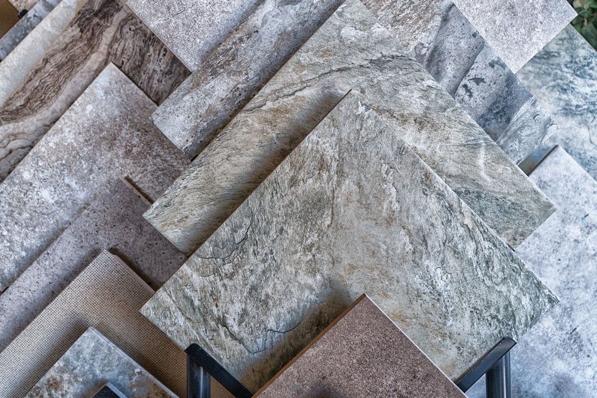 Display of various textured gray and beige ceramic tiles.