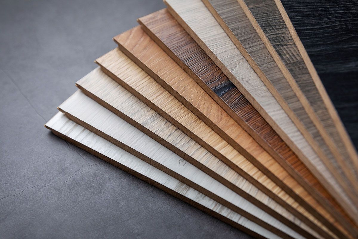 Various wood flooring samples in different shades, arranged in a fan shape on a dark surface.