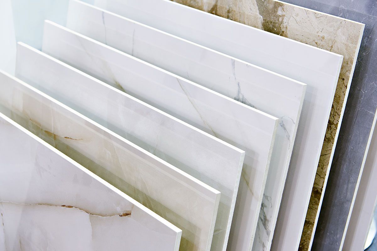 Tiles in various shades of white, beige, and gray, arranged at an angle in a display.