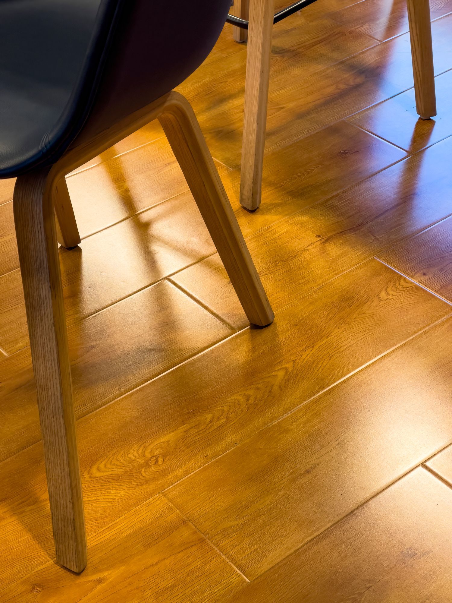 Wooden floor with sunlight reflecting off it, and chair legs. Wooden floor with sunlight reflecting off it, and chair legs.
