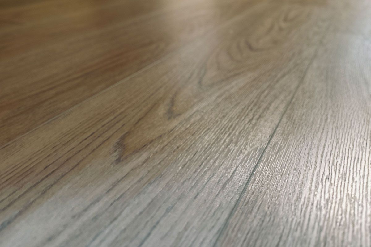 Close-up of light brown wooden floorboards, showing wood grain and sheen.