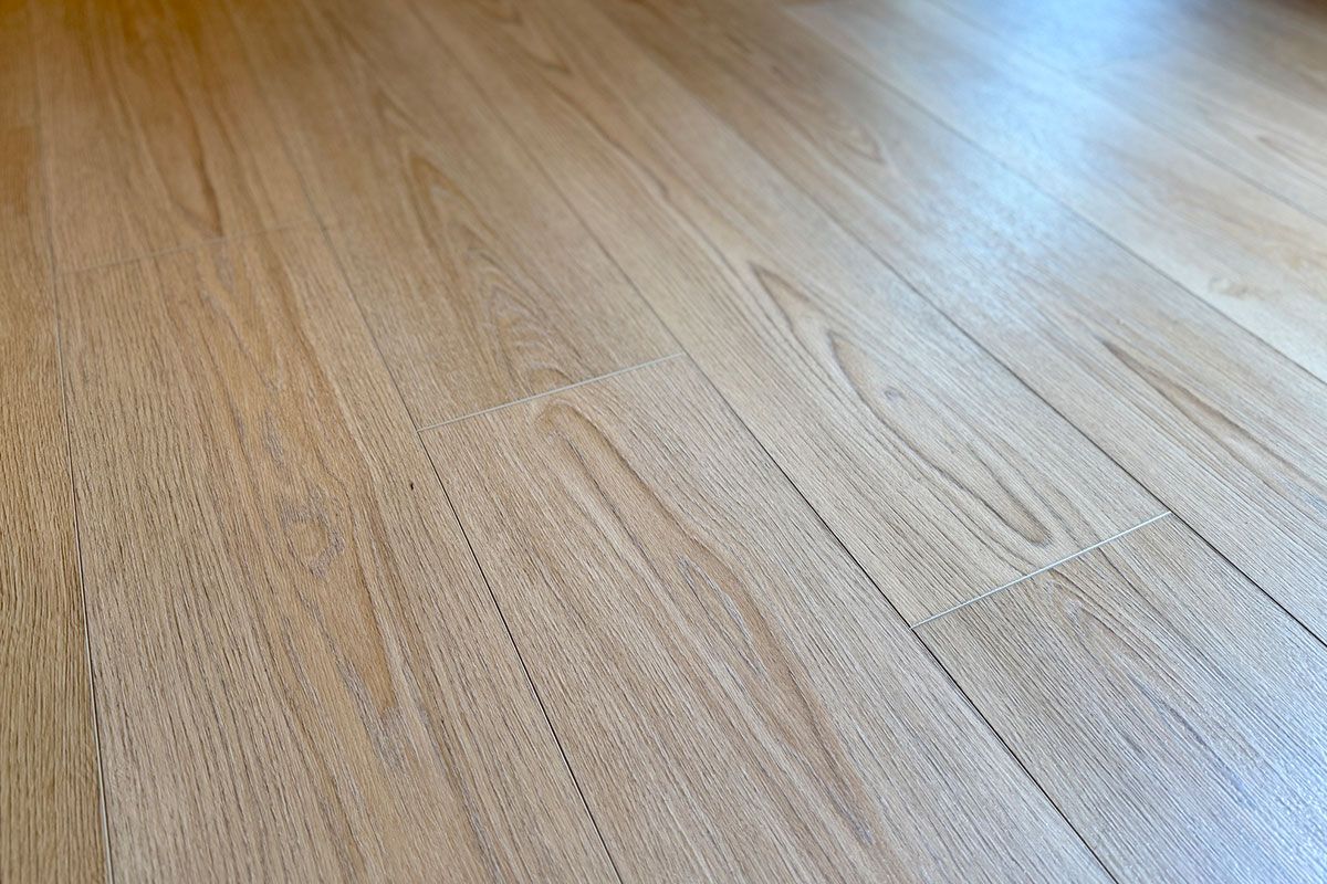 Close-up of light-colored wooden floorboards, with subtle grain patterns and visible seams.