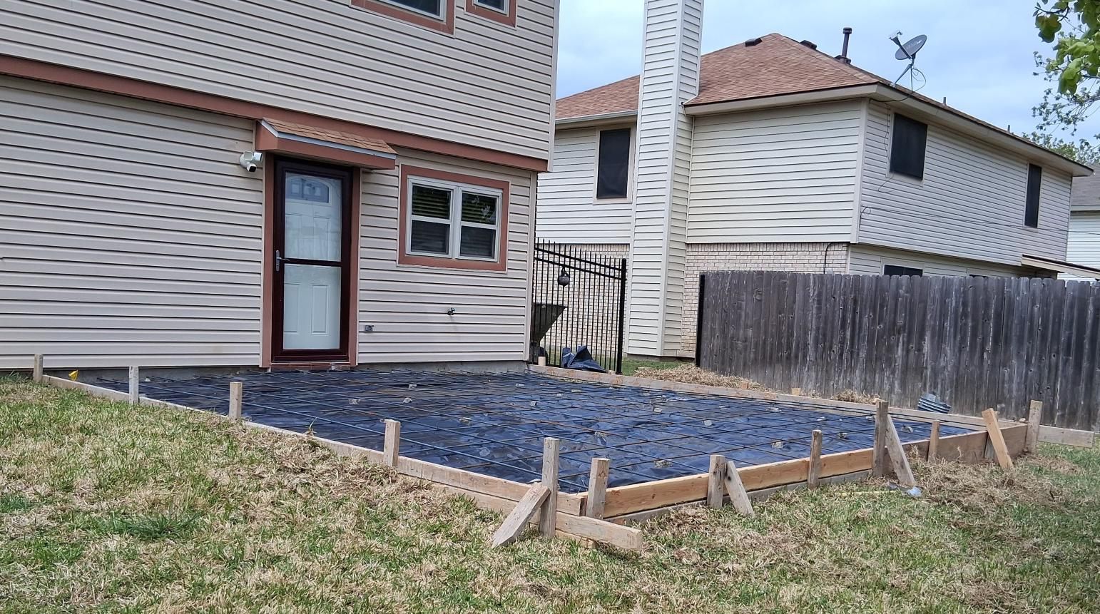 A gravel-filled rectangular area framed by wooden boards for a patio project in a residential backyard.
