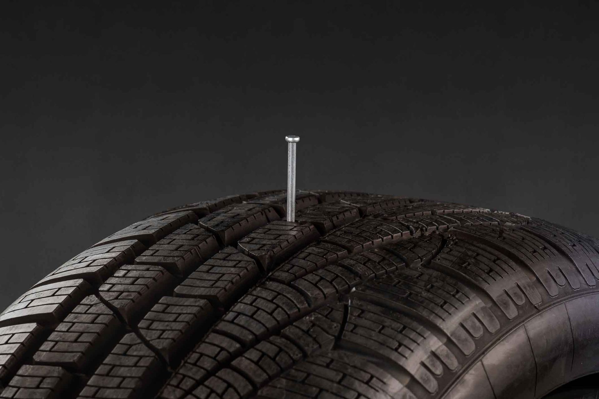 A tire with a nail sticking out of it.