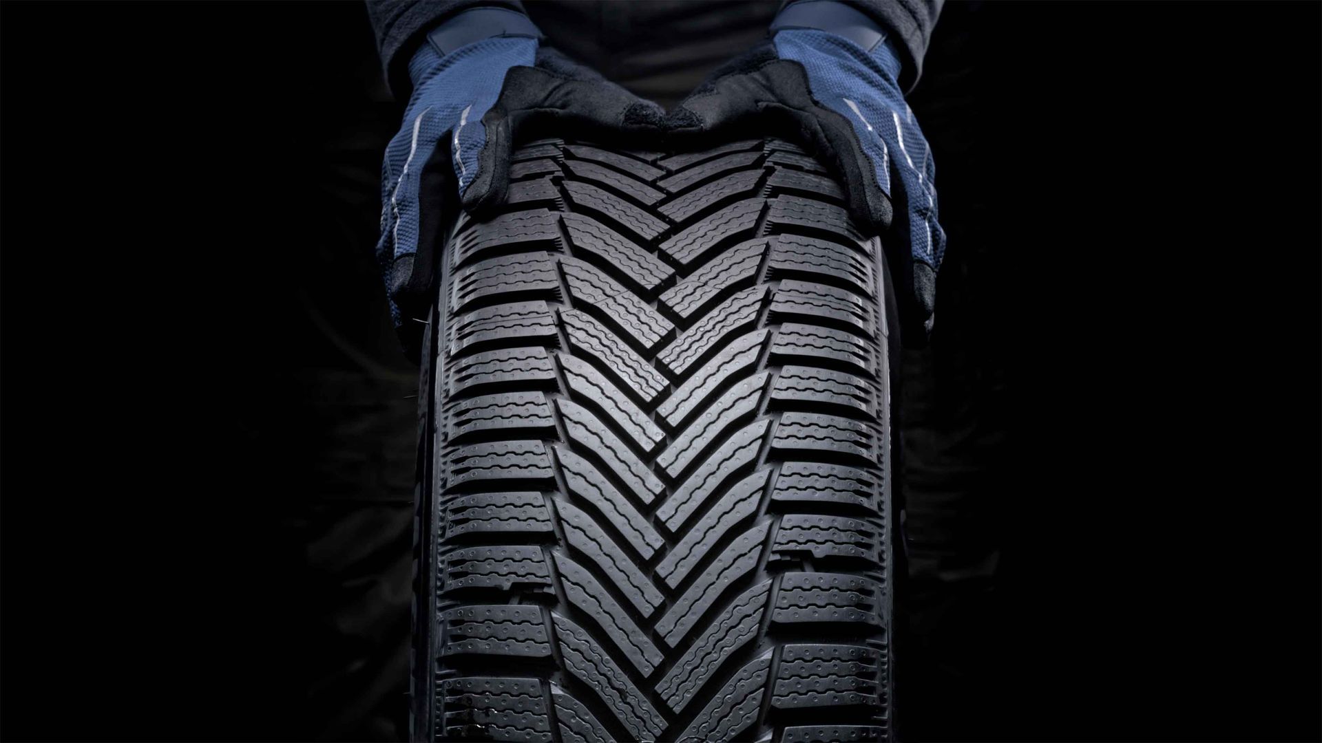 A person wearing gloves is holding a tire in their hands.