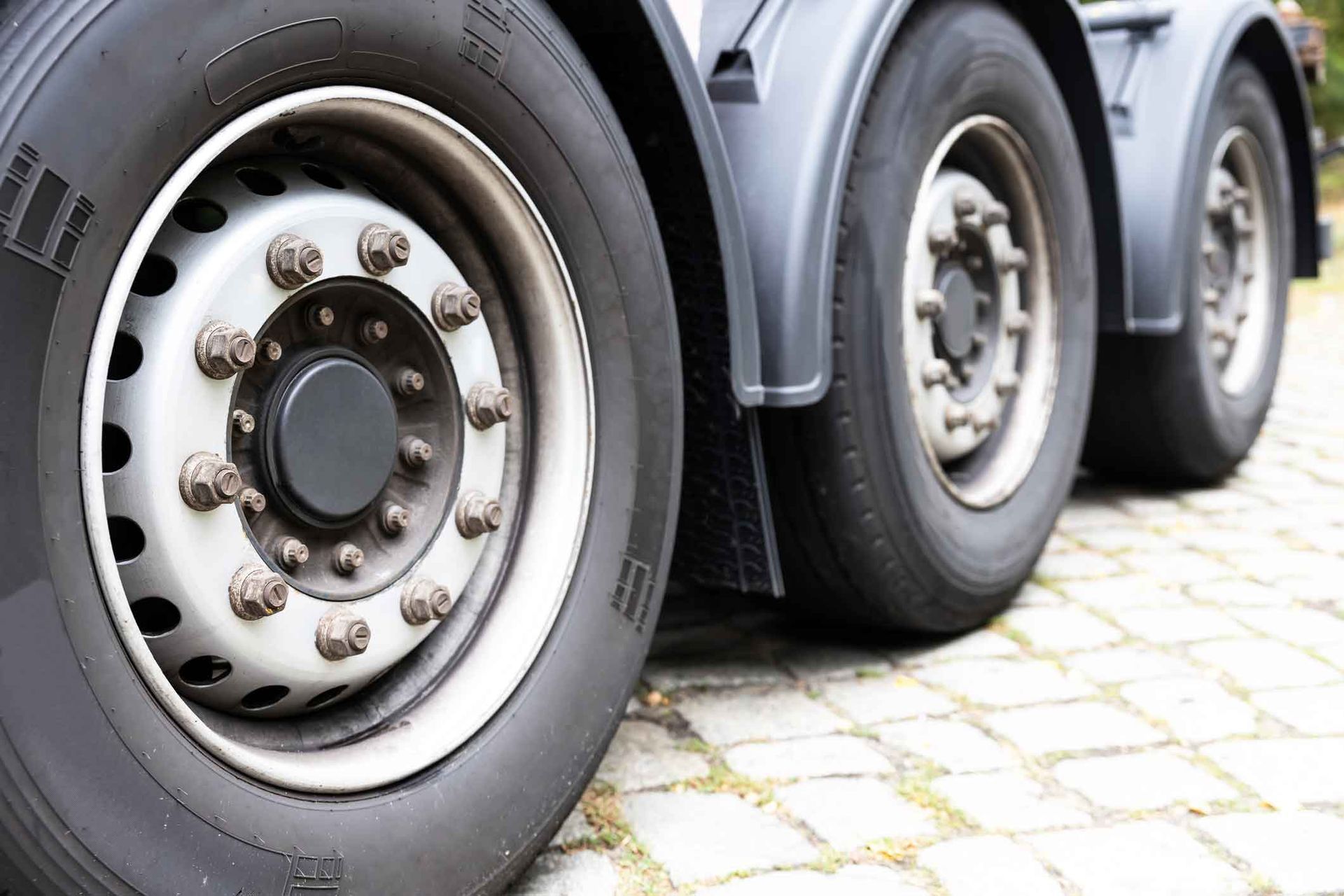 A close up of a truck 's tires on a cobblestone road.