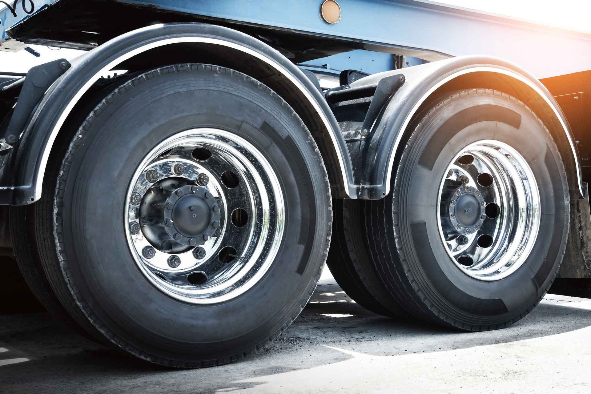 A close up of a semi truck 's tires and fenders.