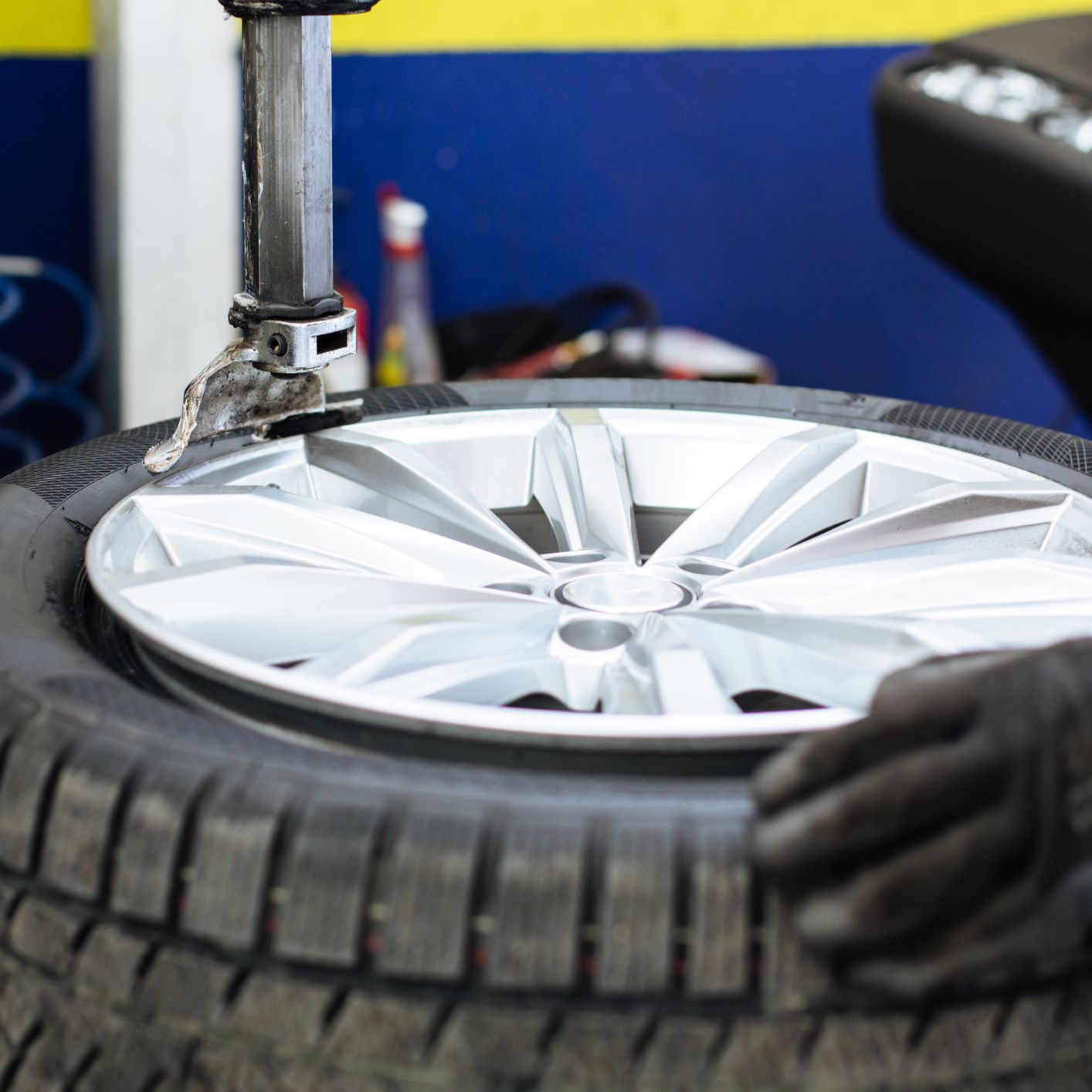 Close-up of a mechanic using black gloves, changing a car tyre inside a tyre shop.