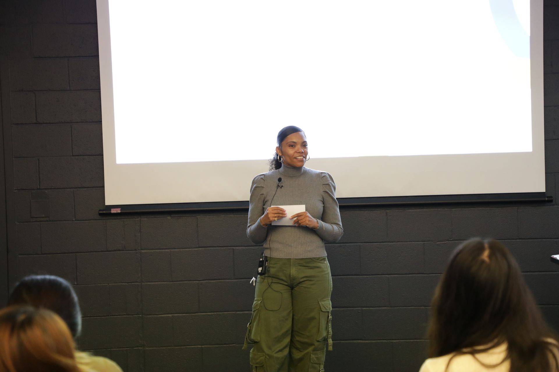 Three people in a therapy session: One man on a black couch, two women in chairs. Bright, minimalist room.