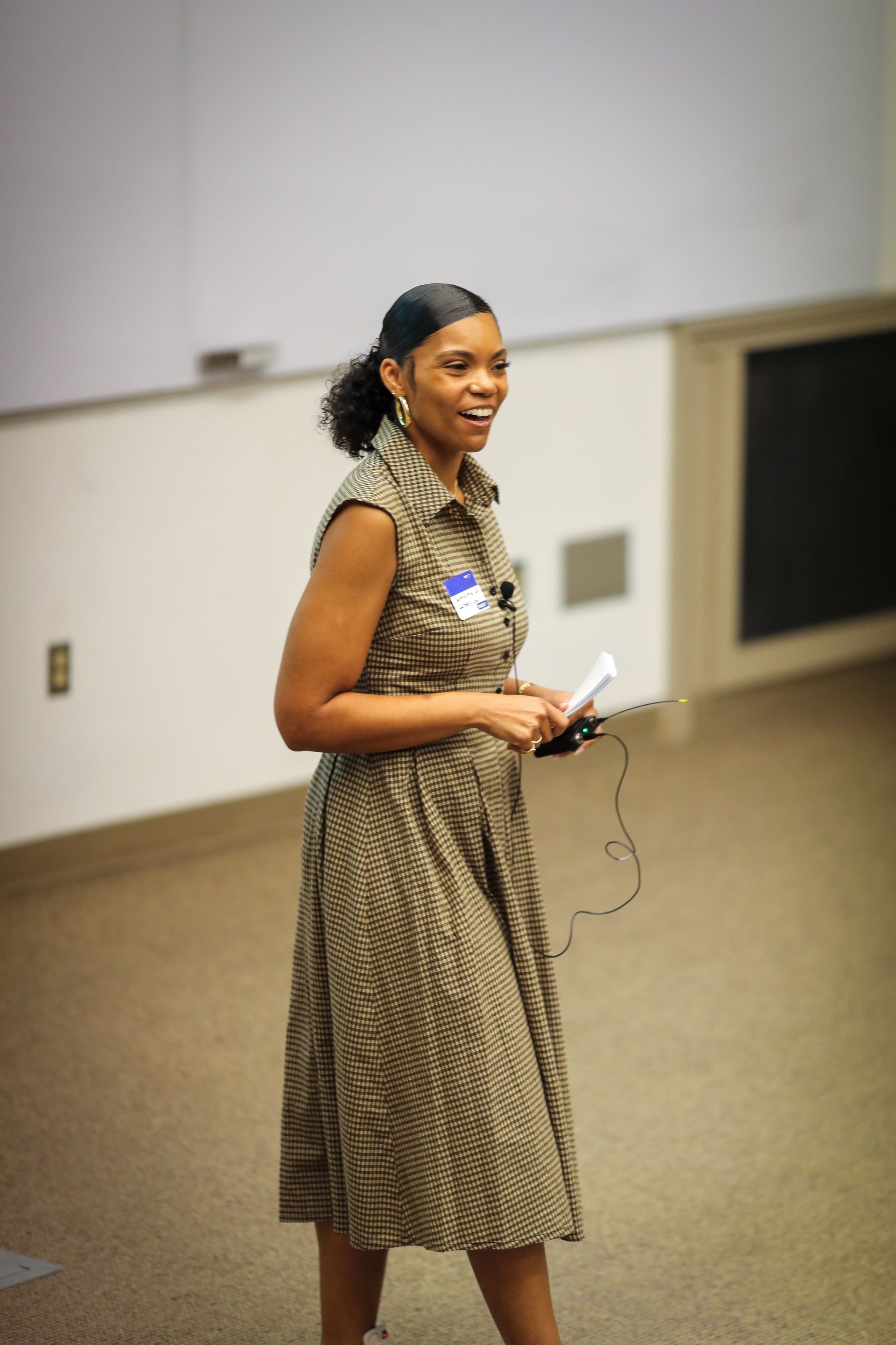Three people seated on a bench, looking at papers and a laptop in front of a modern building.