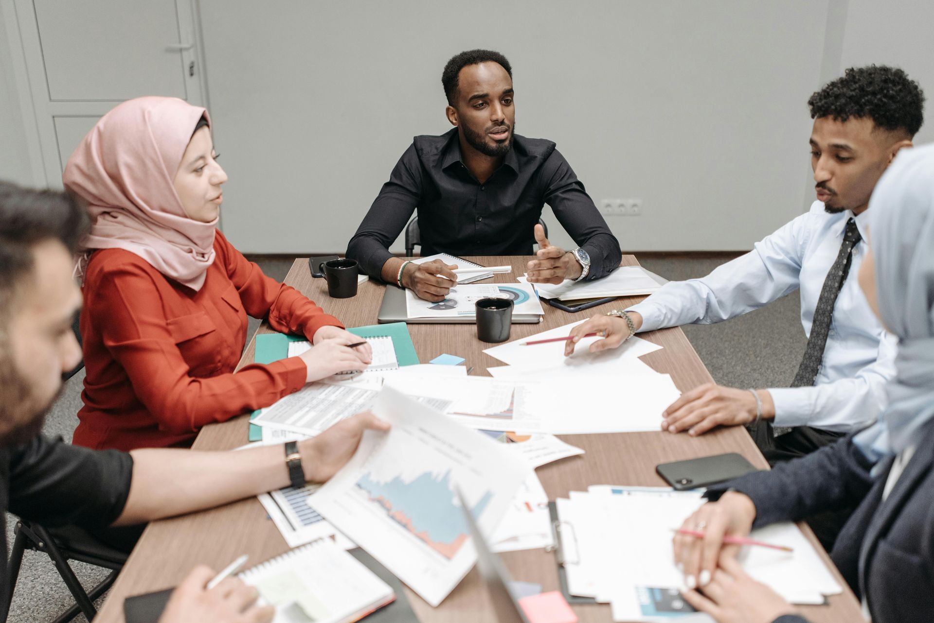 Group of people in meeting around a table with papers, discussing.