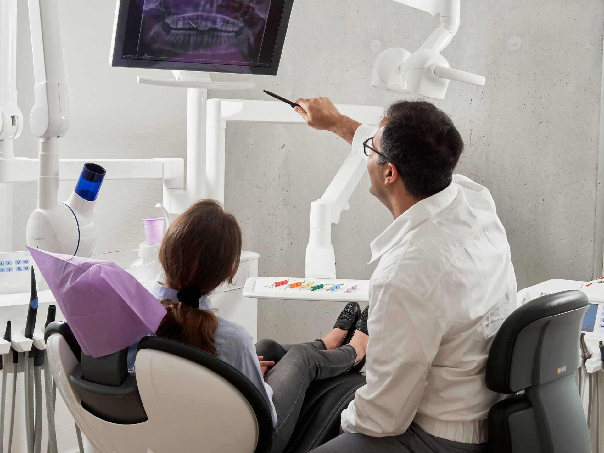 A dentist is showing a patient a picture of their teeth on a monitor.