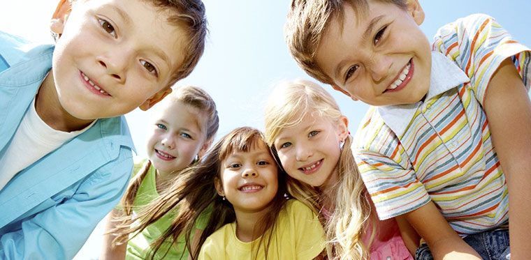 A group of children are posing for a picture together and smiling.