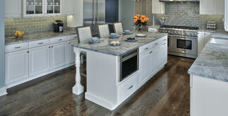 A kitchen with white cabinets , granite counter tops , and stainless steel appliances.