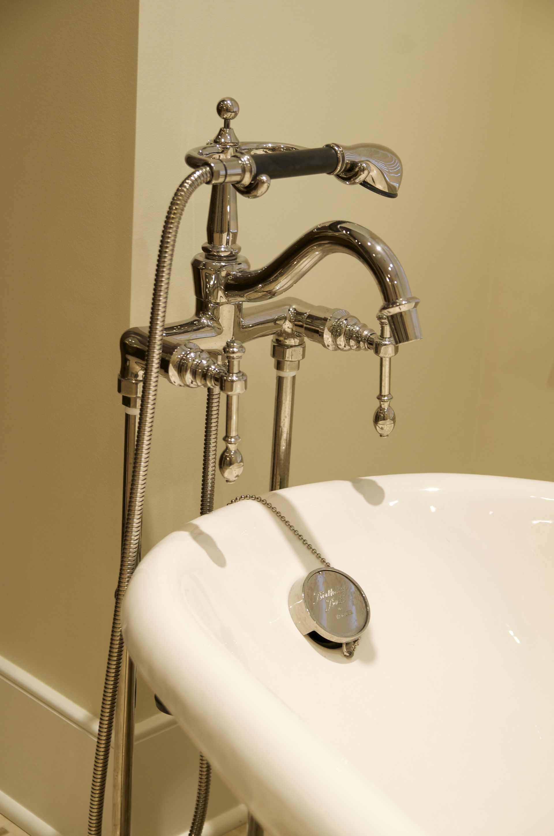 A bathtub with a faucet and hose attached to it