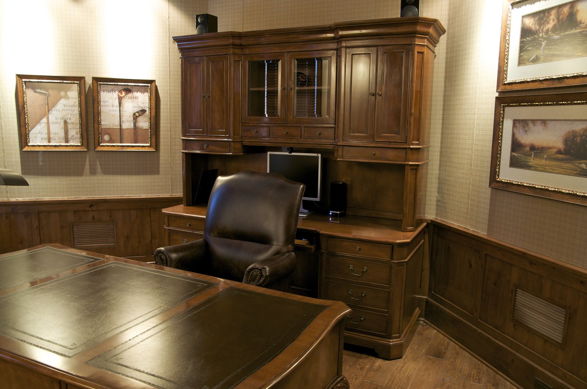 A home office with a desk and chair and paintings on the wall