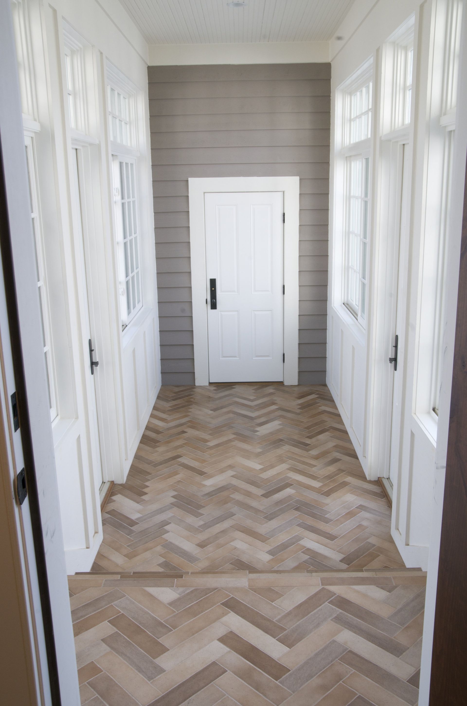 A long hallway with a herringbone floor and white doors.