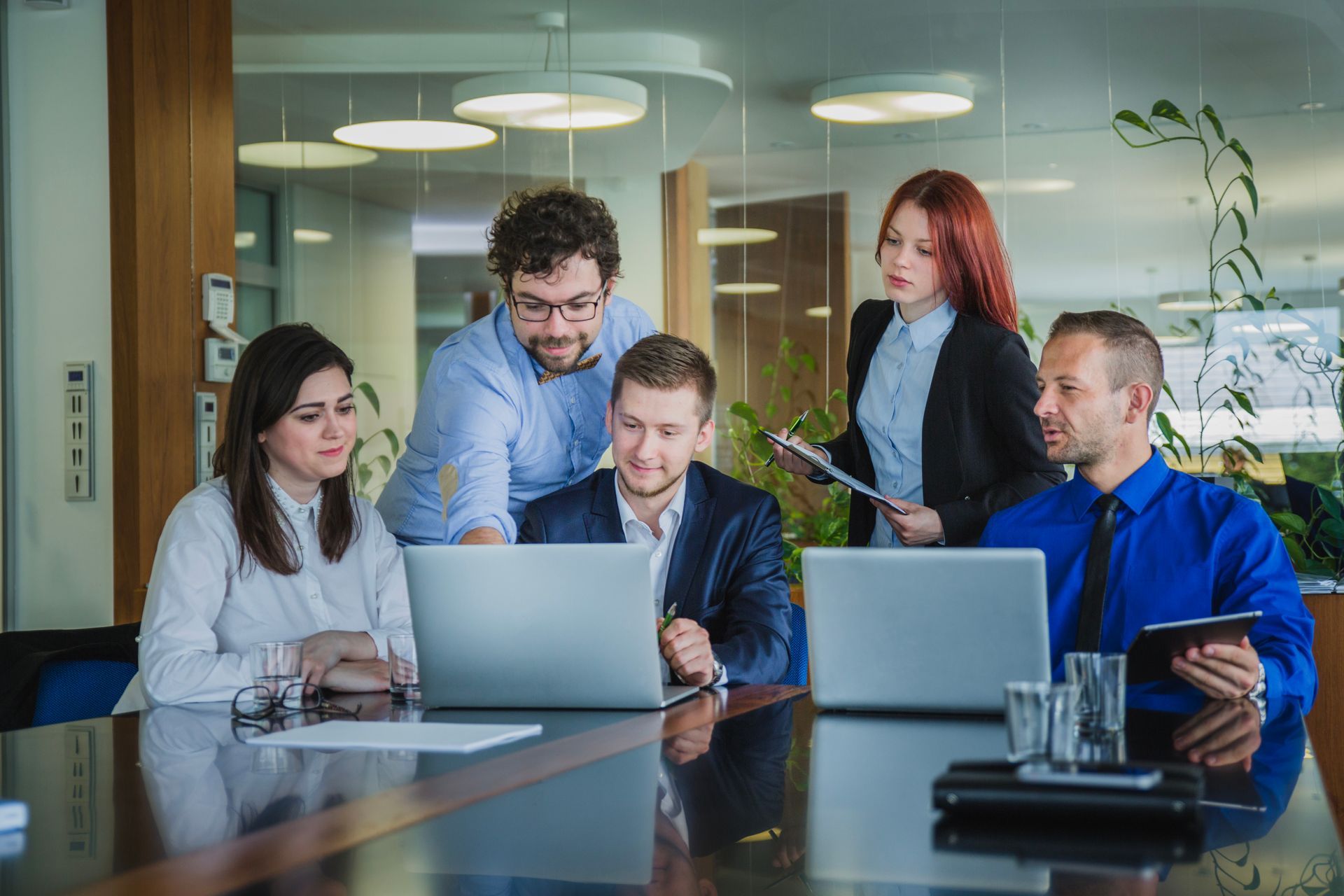 A group of people are sitting around a table looking at laptops.