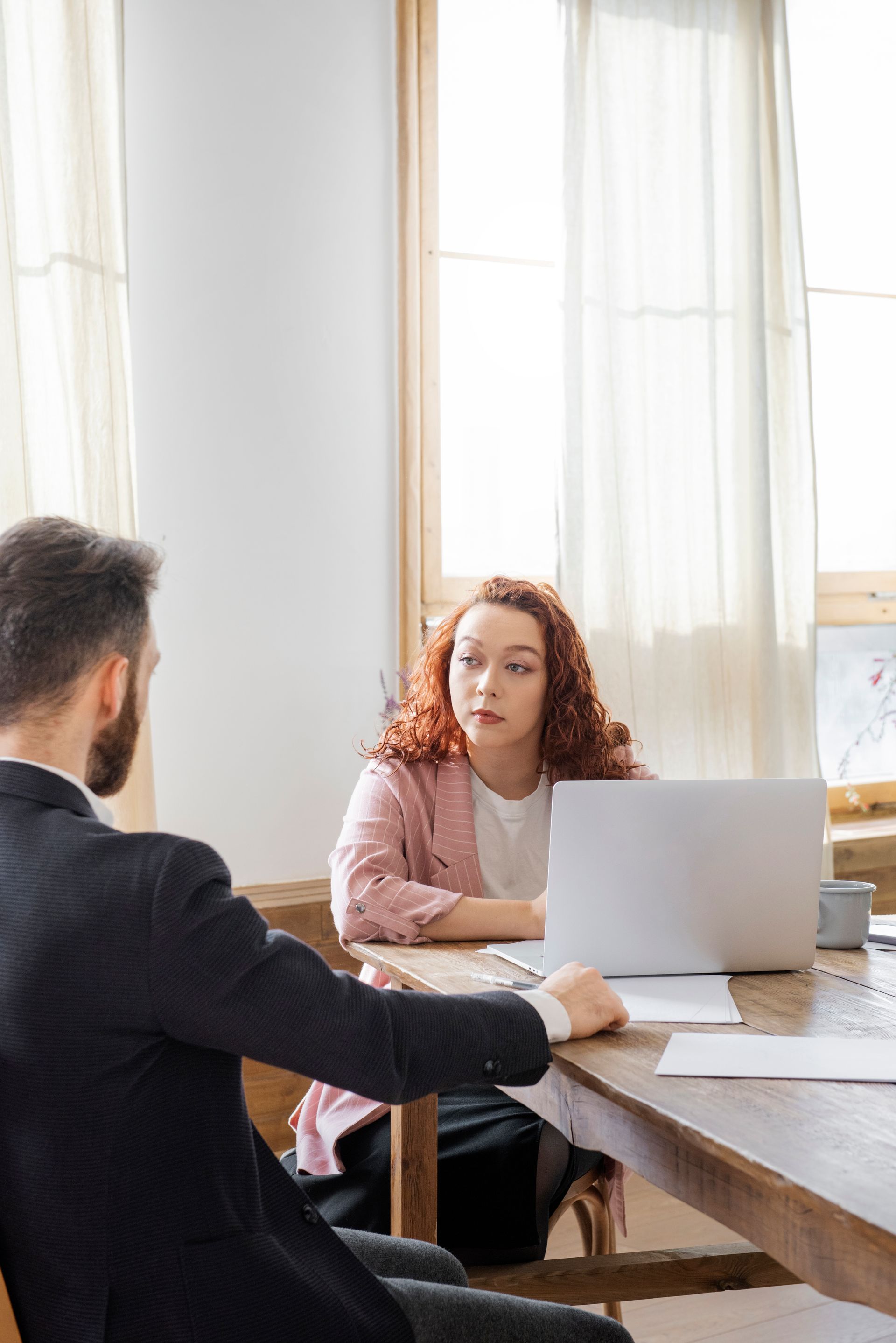 A man and a woman are sitting at a table with a laptop.