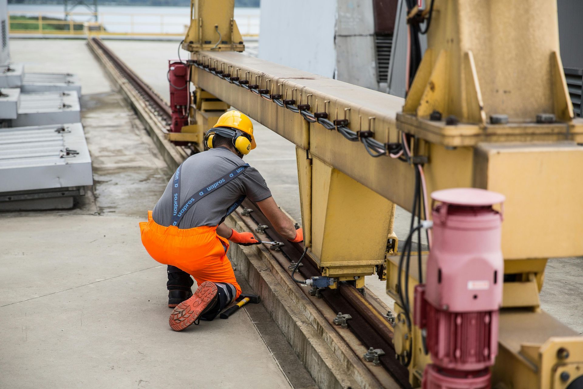 A man is working on a crane on a railroad track.