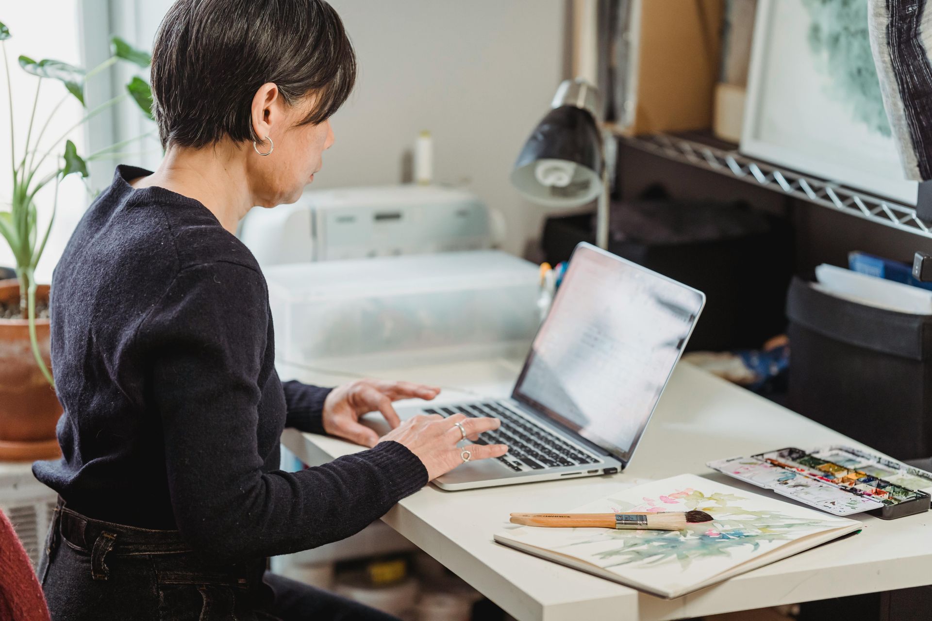 A woman is sitting at a desk using a laptop computer.