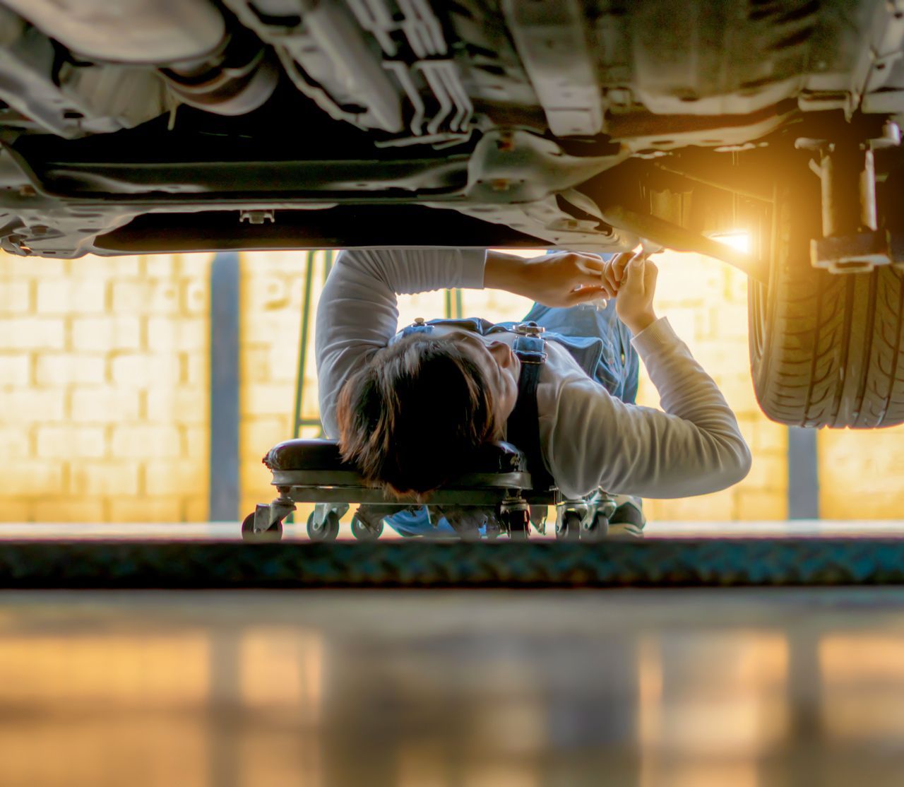 A man is working under a car in a garage.