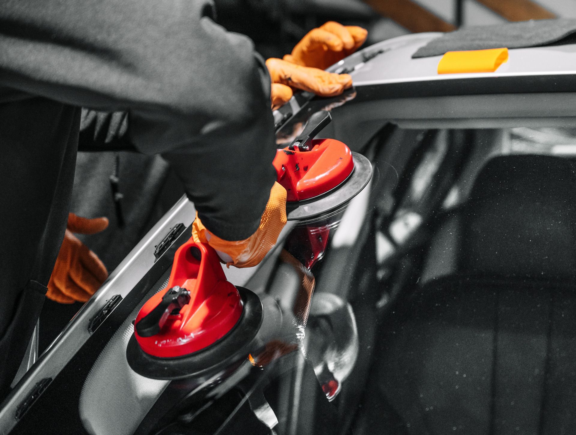 A man is installing a windshield on a car.