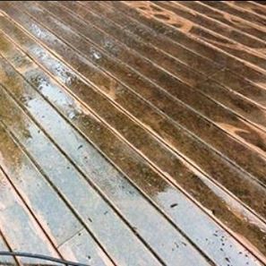 Wet wooden deck, close-up, diagonal planks, showing water and discoloration.