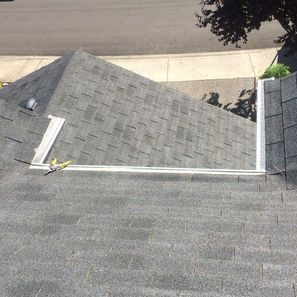 Gray shingle roof, angled section with aluminum flashing. Sunny outdoor setting.