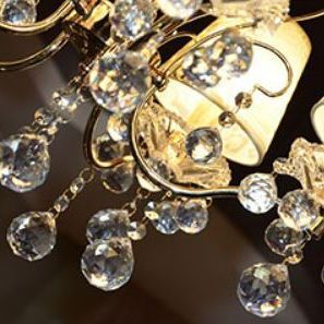 Close-up of a crystal chandelier with lightbulb and gold accents, with many dangling crystals.