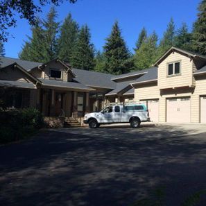 Beige house with attached garage, trees in the background, a white pickup truck in the driveway.
