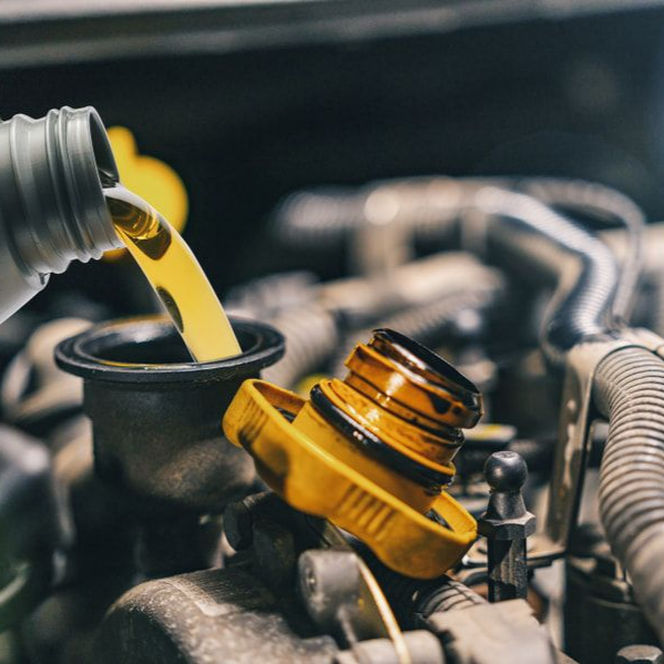 Yellow Oil Being Poured Into a Car Engine, Next to an Open Oil Cap — Alice Springs Auto Parts in Ciccone, NT