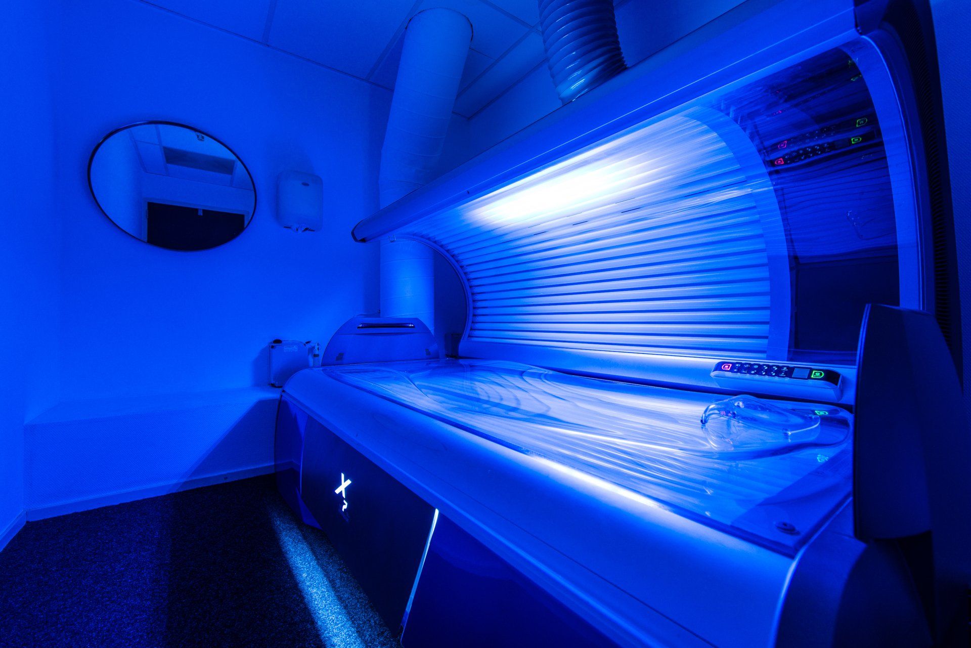 Zonnebank in een blauw verlichte kamer met een spiegel aan de muur.