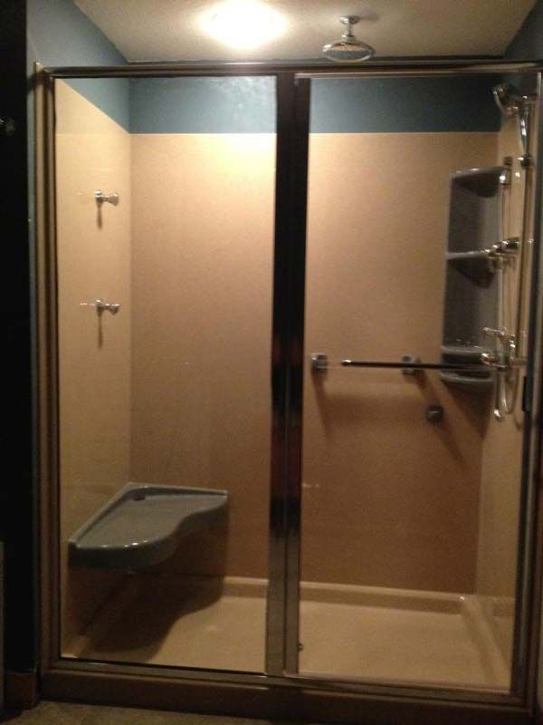 Shower with glass doors, built-in seat, grab bar, and shelving. Beige walls, blue trim.