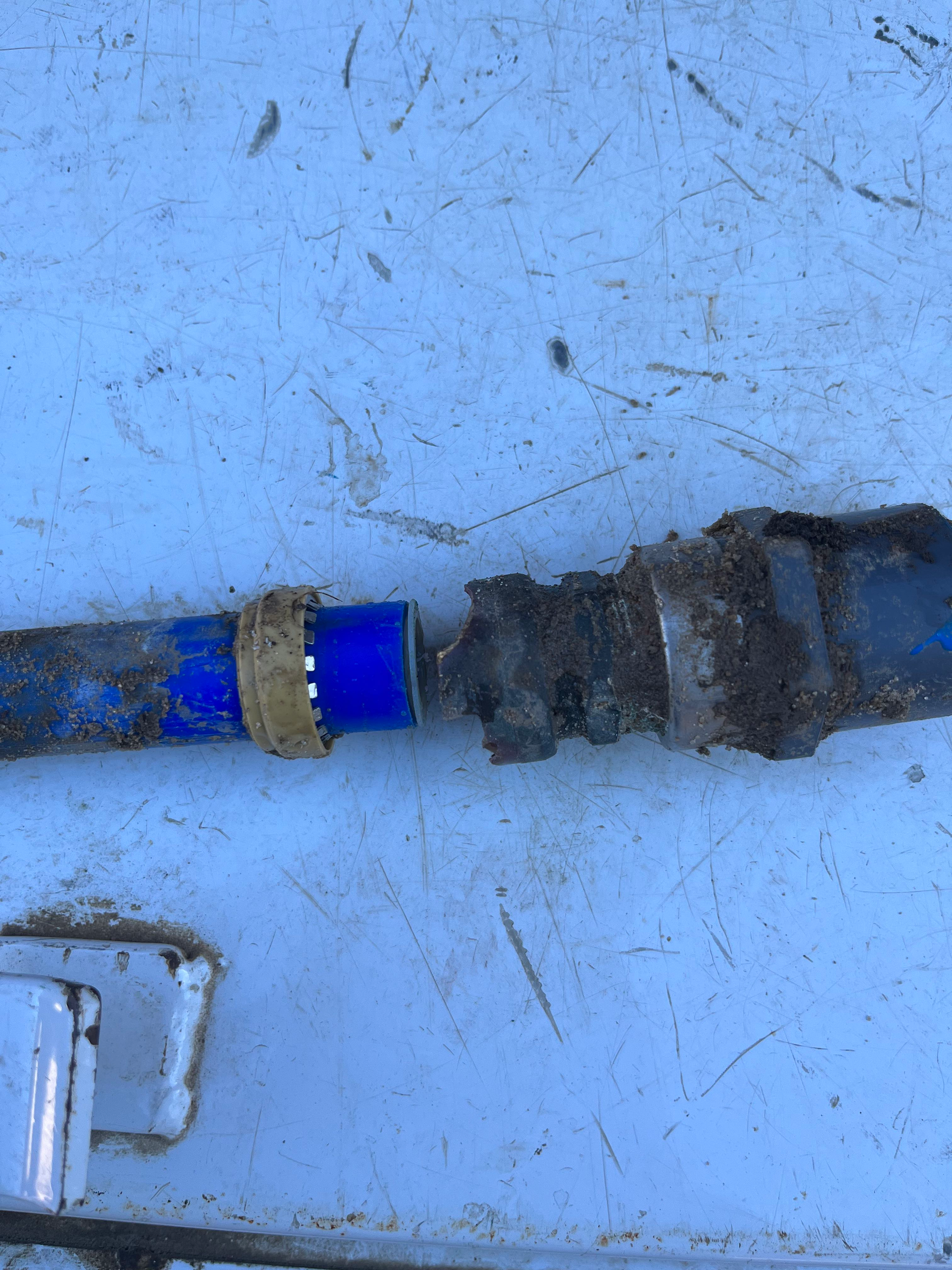 Two pieces of blue plastic tubing with a broken connection, lying on a light blue surface.