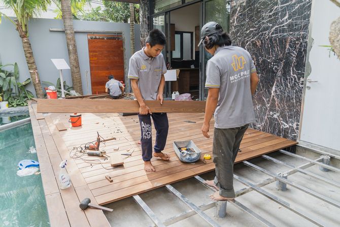 Contractors repairing a backyard deck