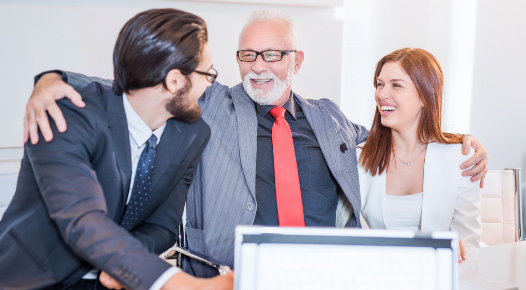 A group of business people are hugging each other in an office.