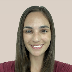 A woman with long hair is smiling and wearing a red shirt